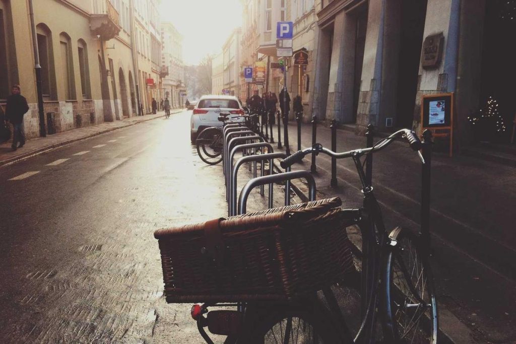City street with parked bicycles, early morning light, historic buildings, and car parked on quiet road.