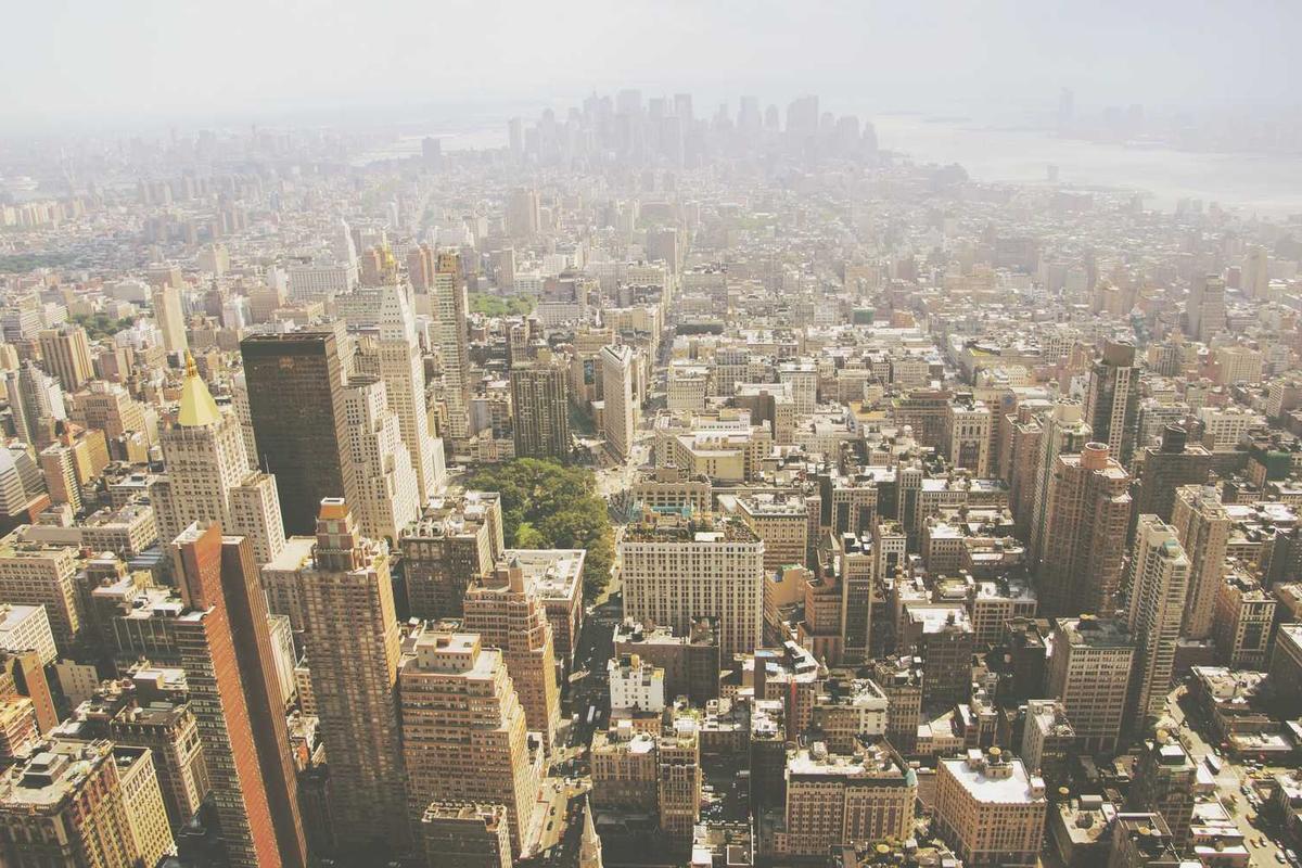 Aerial view of a densely packed New York City skyline with skyscrapers and Central Park in the background.